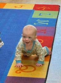 Child crawling on a colorful alphabet rug