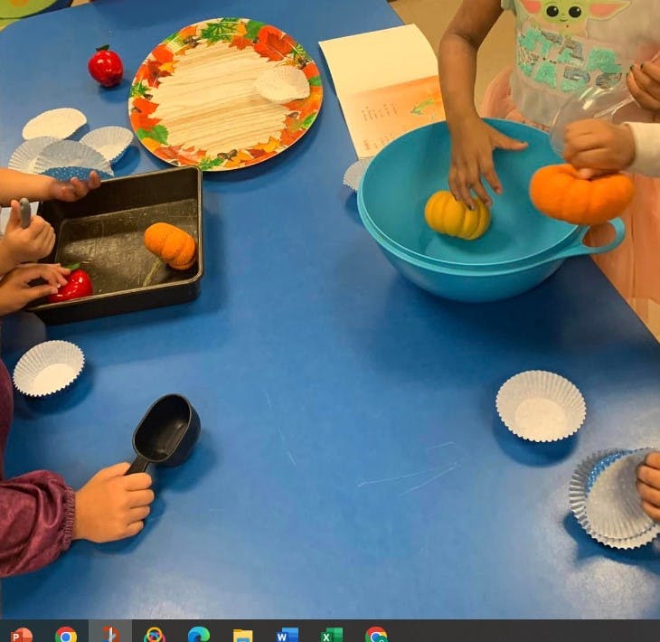 Children playing with small pumpkins and baking supplies on a blue table