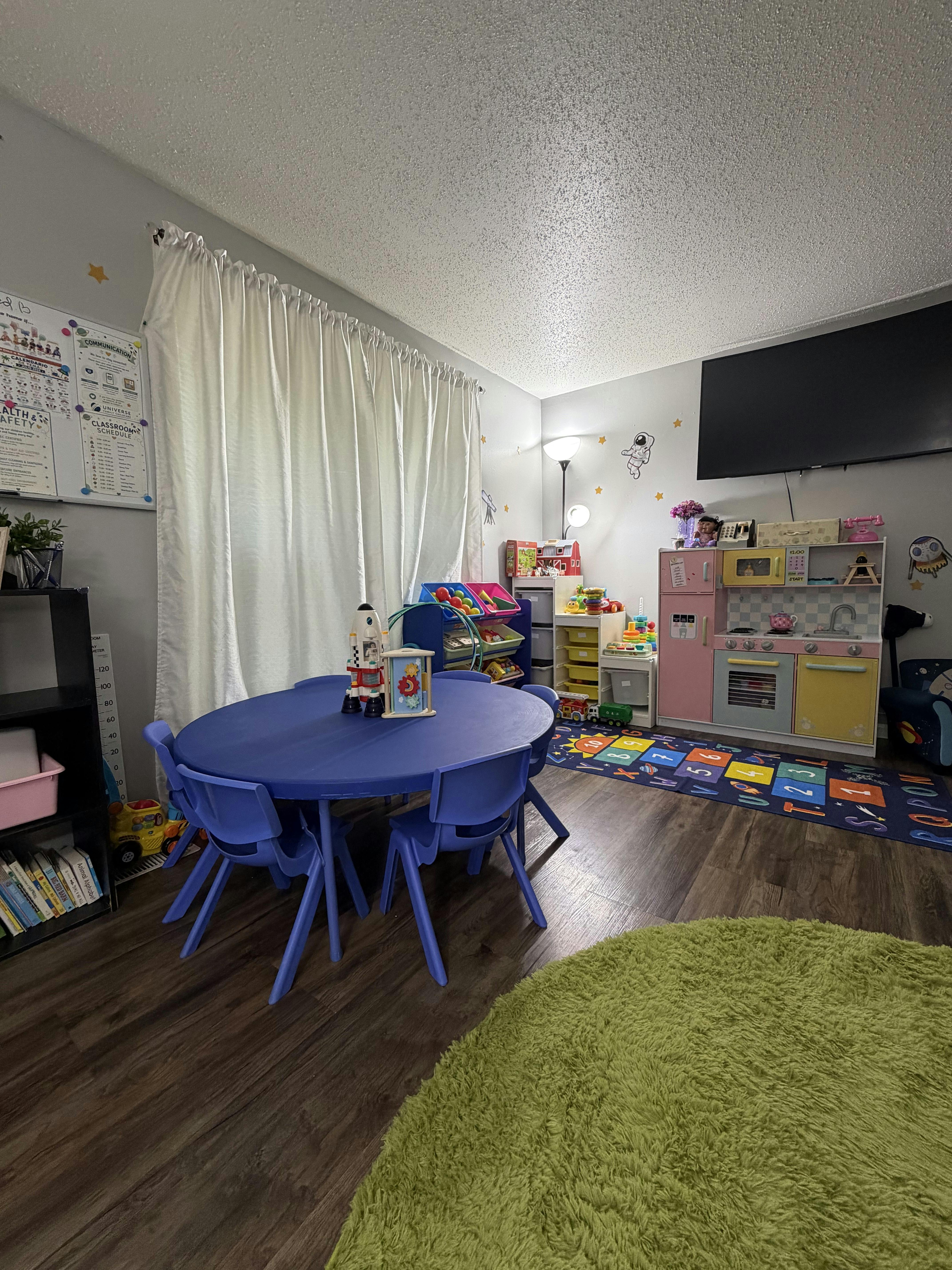 Child playroom with a blue table and chairs and a toy kitchen