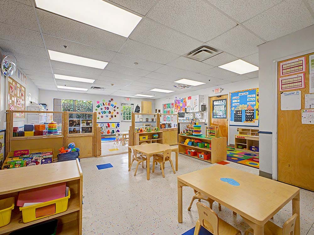 Classroom with small wooden tables and chairs, toys, and learning materials