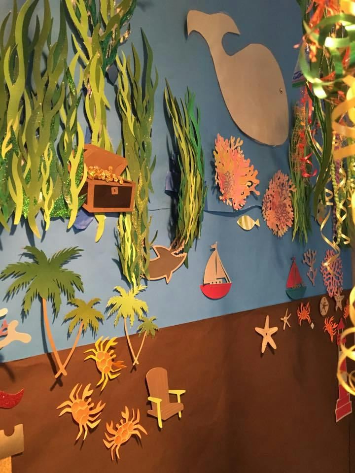 Paper cutouts of an underwater scene with seaweed, coral, fish, and a treasure chest