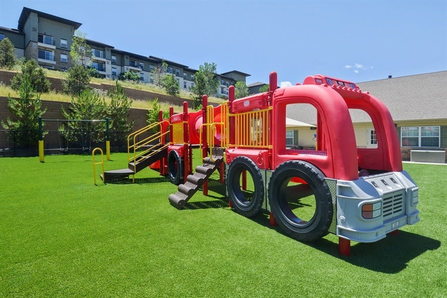 Red fire truck shaped playground equipment on green turf