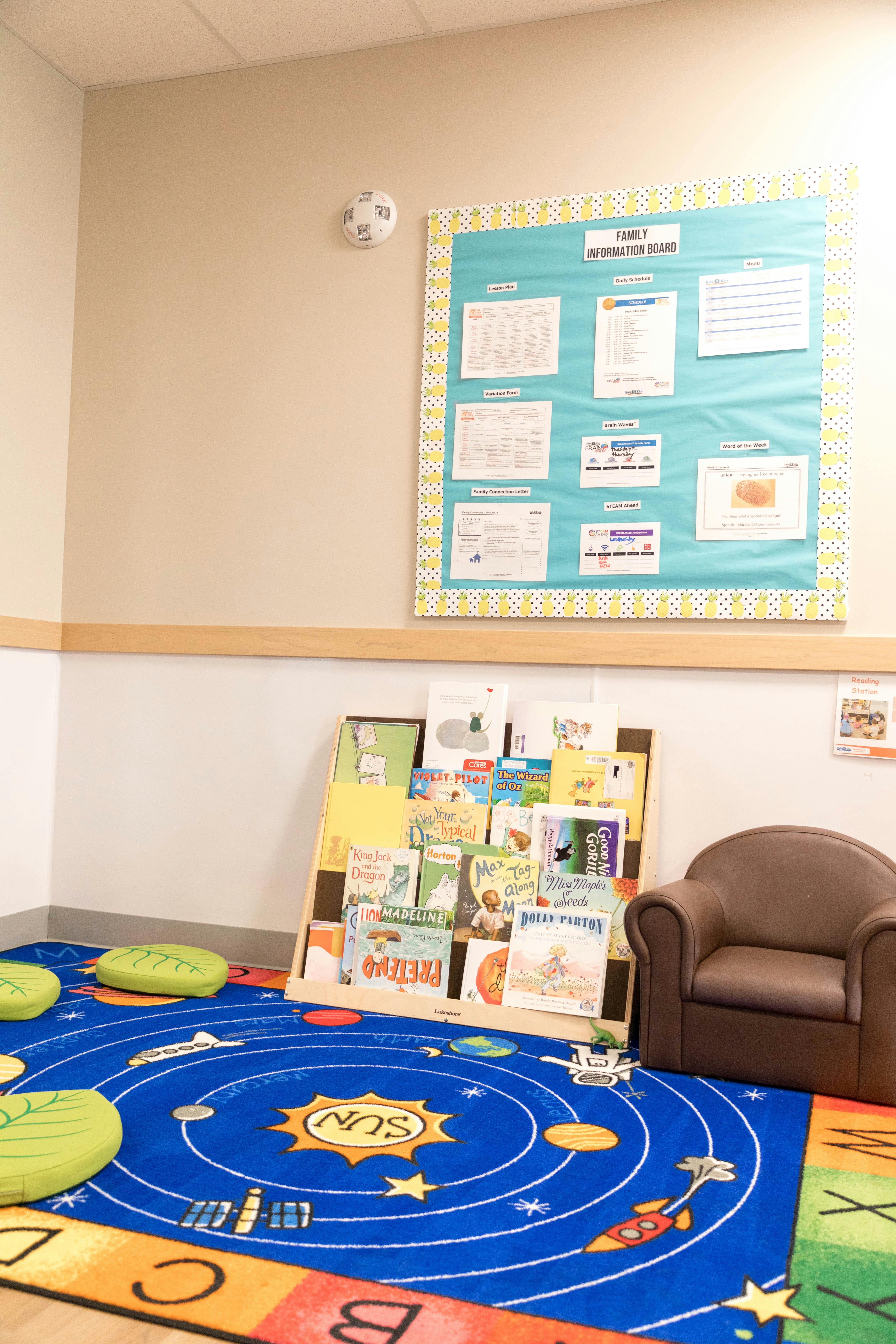 Children's reading corner with a bookshelf, armchair, and solar system rug