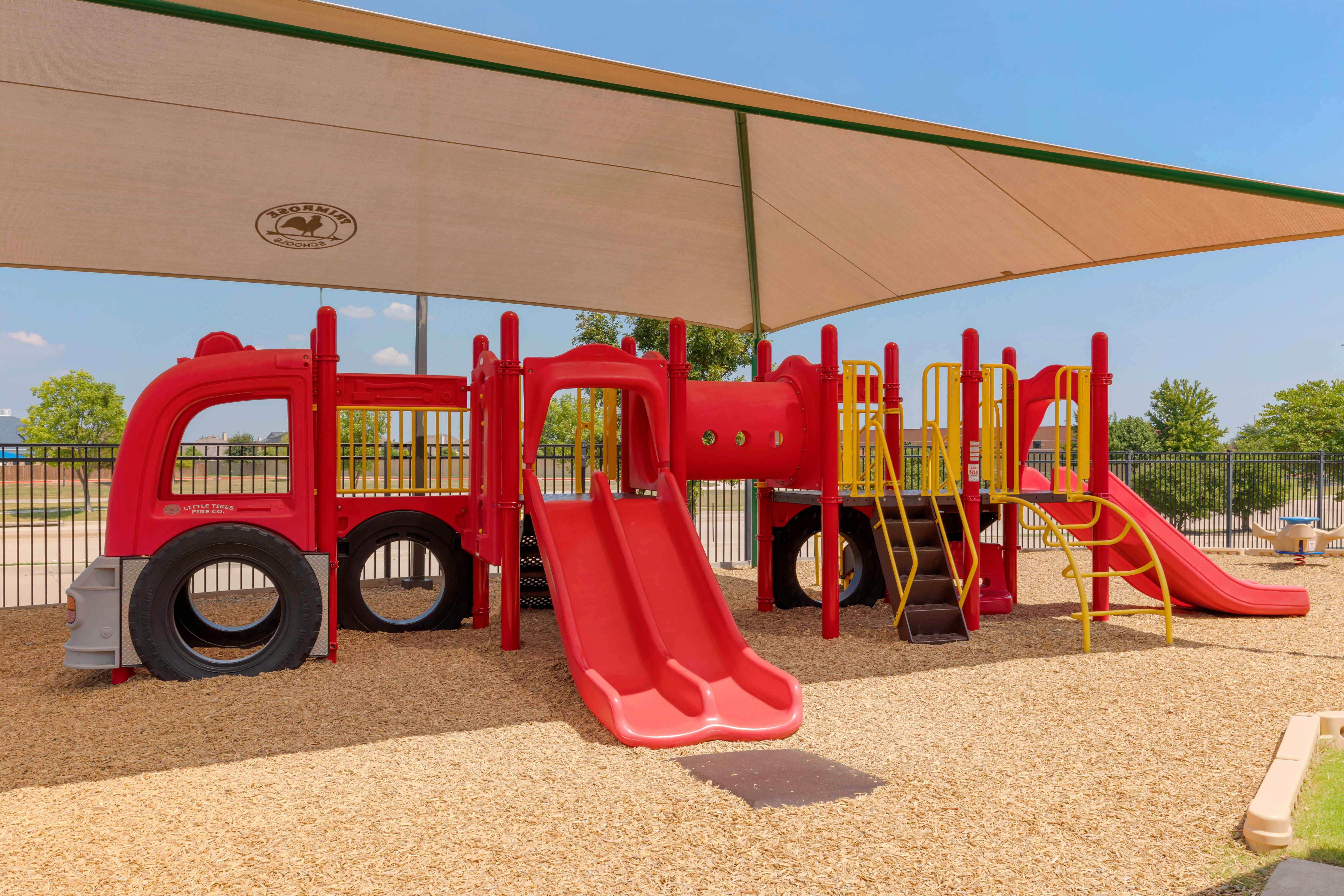 Red and yellow playground equipment with slides and a fire truck feature