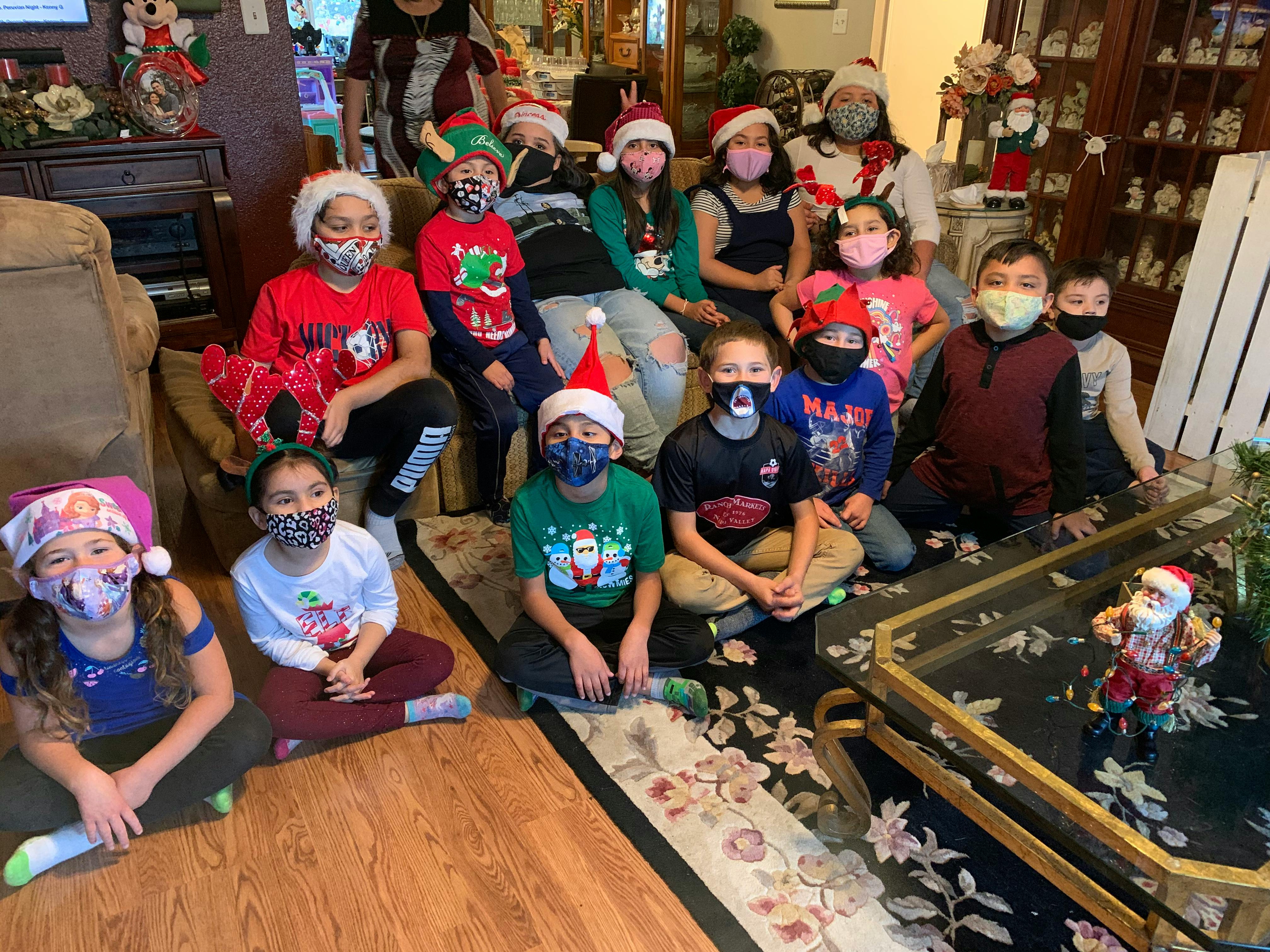 Group of children and adults wearing Santa hats and face masks