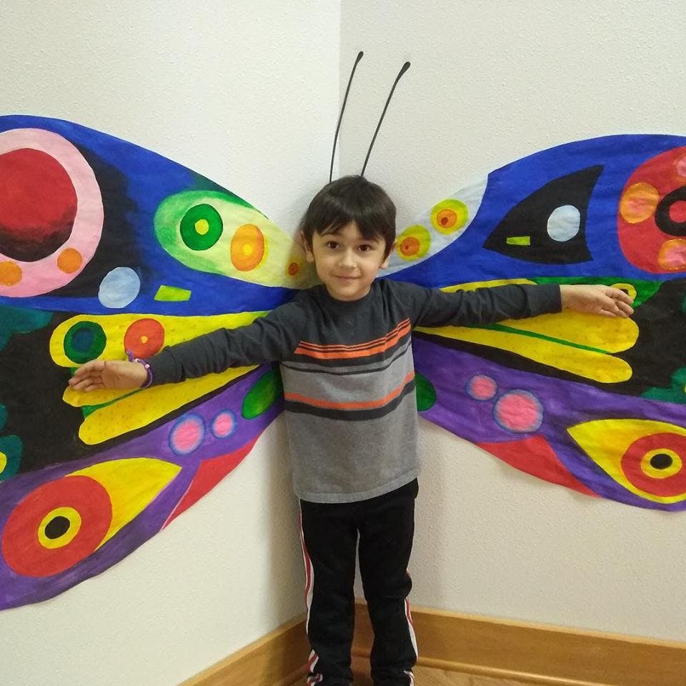 Child standing in front of colorful butterfly wings