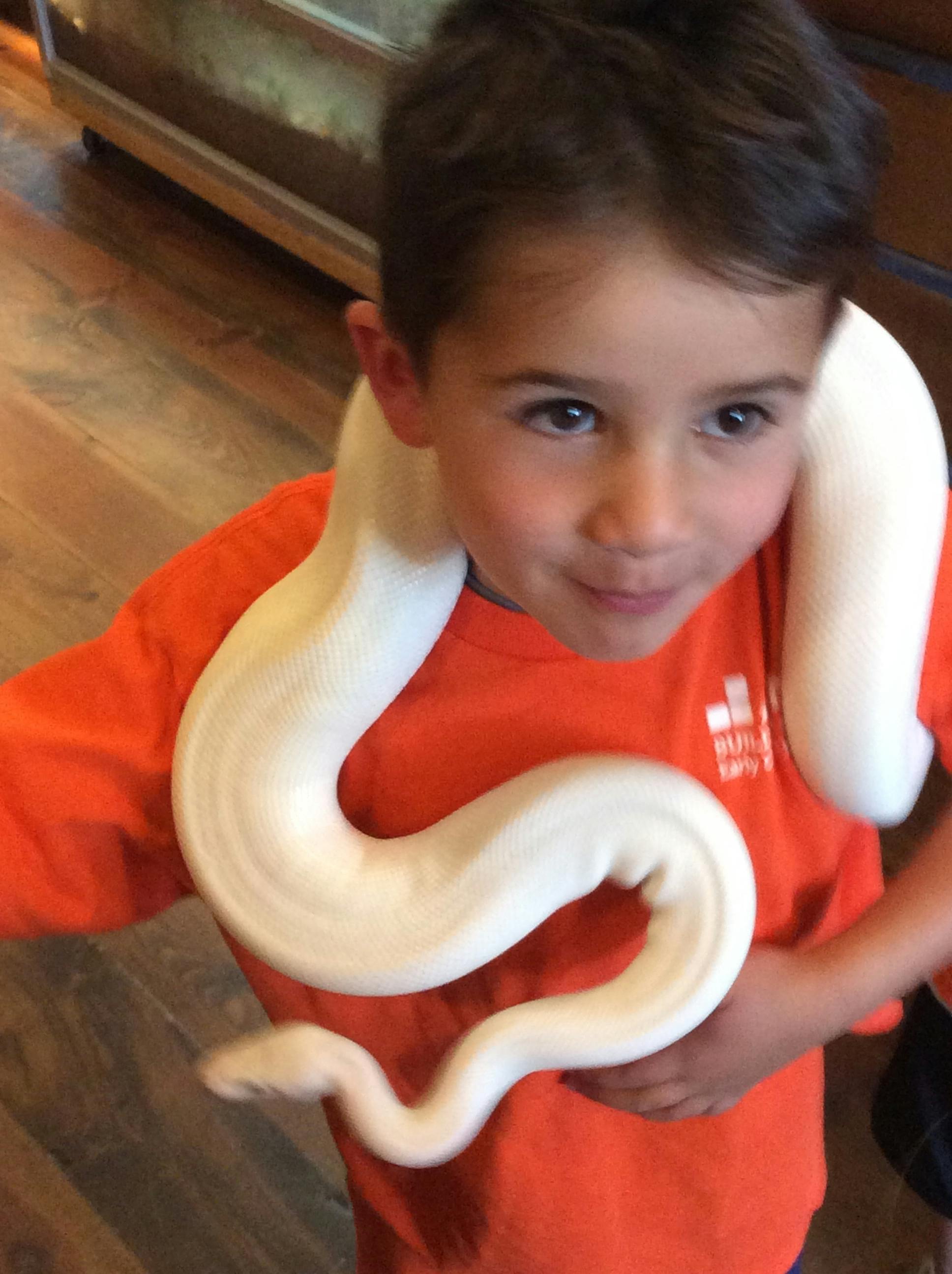 Child with a white snake draped around their neck