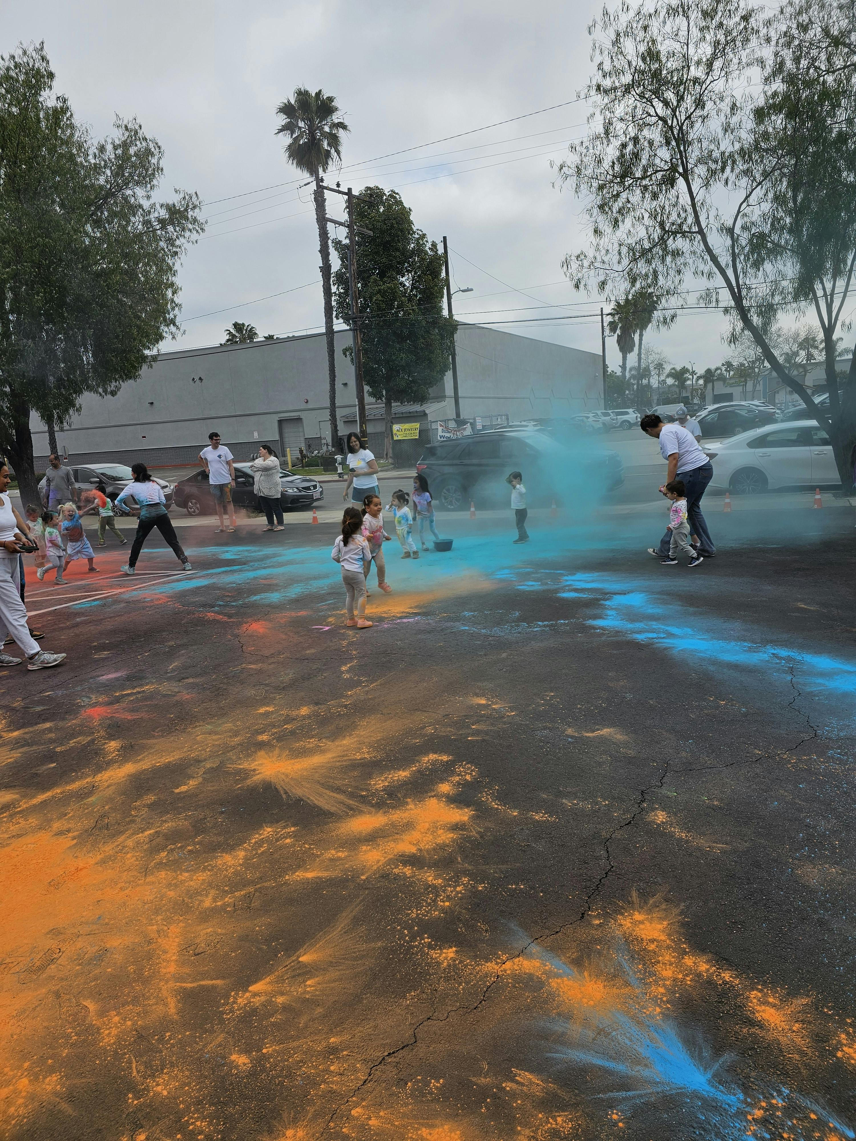 People and children playing with blue and orange powder outdoors
