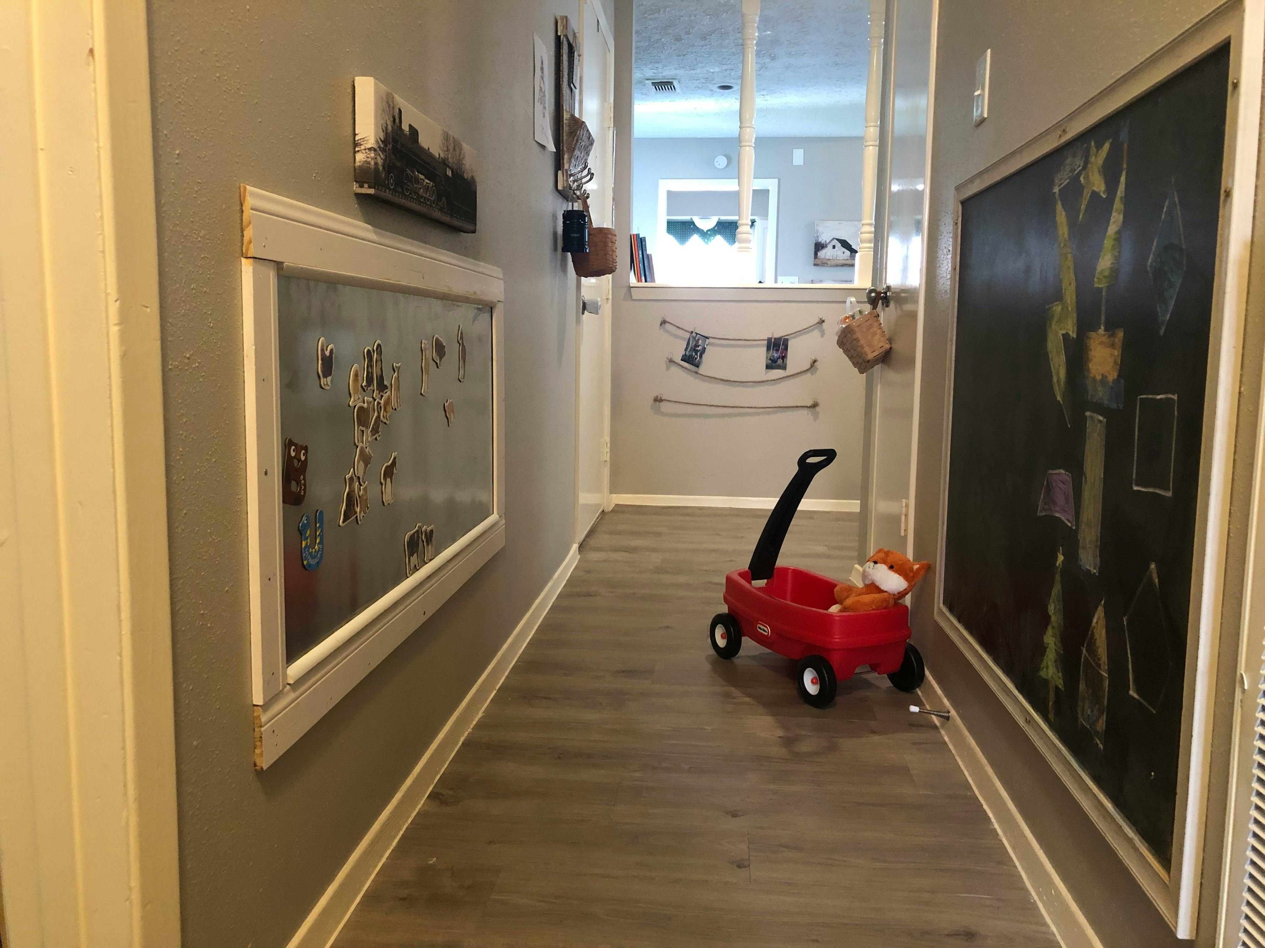 Hallway with a red toy wagon, a framed display, and a large chalkboard