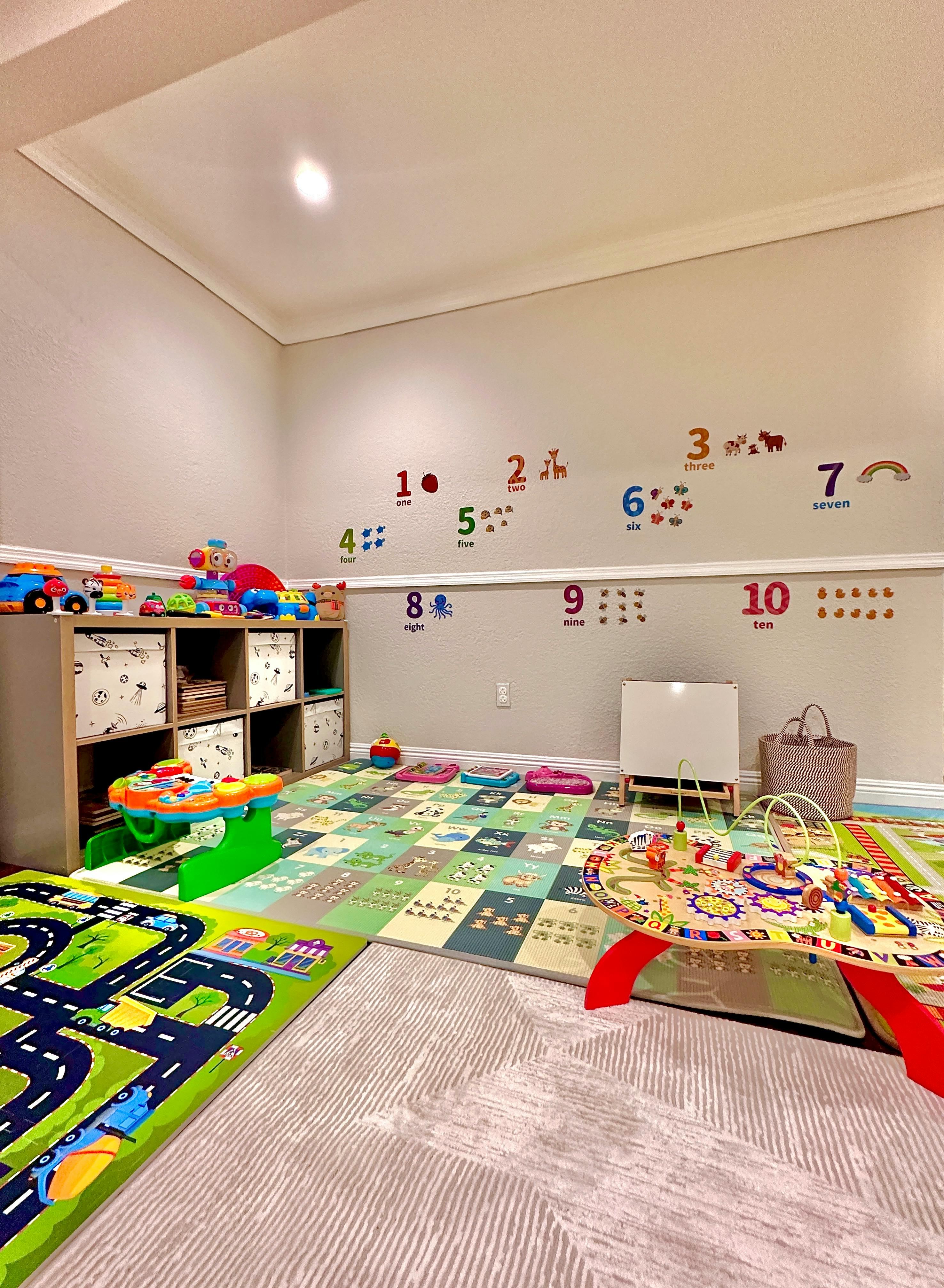 Playroom with colorful rugs, toys, and number decals on the wall
