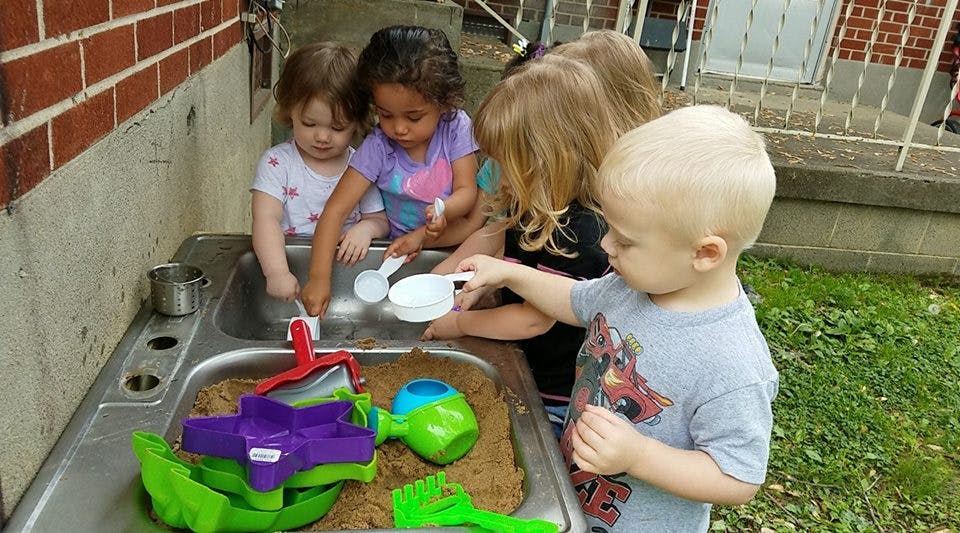 Children playing with sand and water in a sink