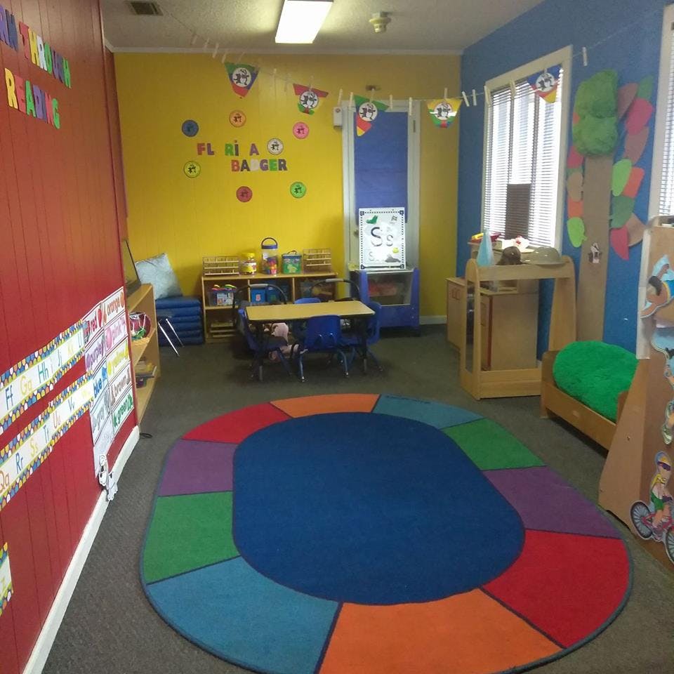 Colorful classroom with a round rug, small tables, and chairs