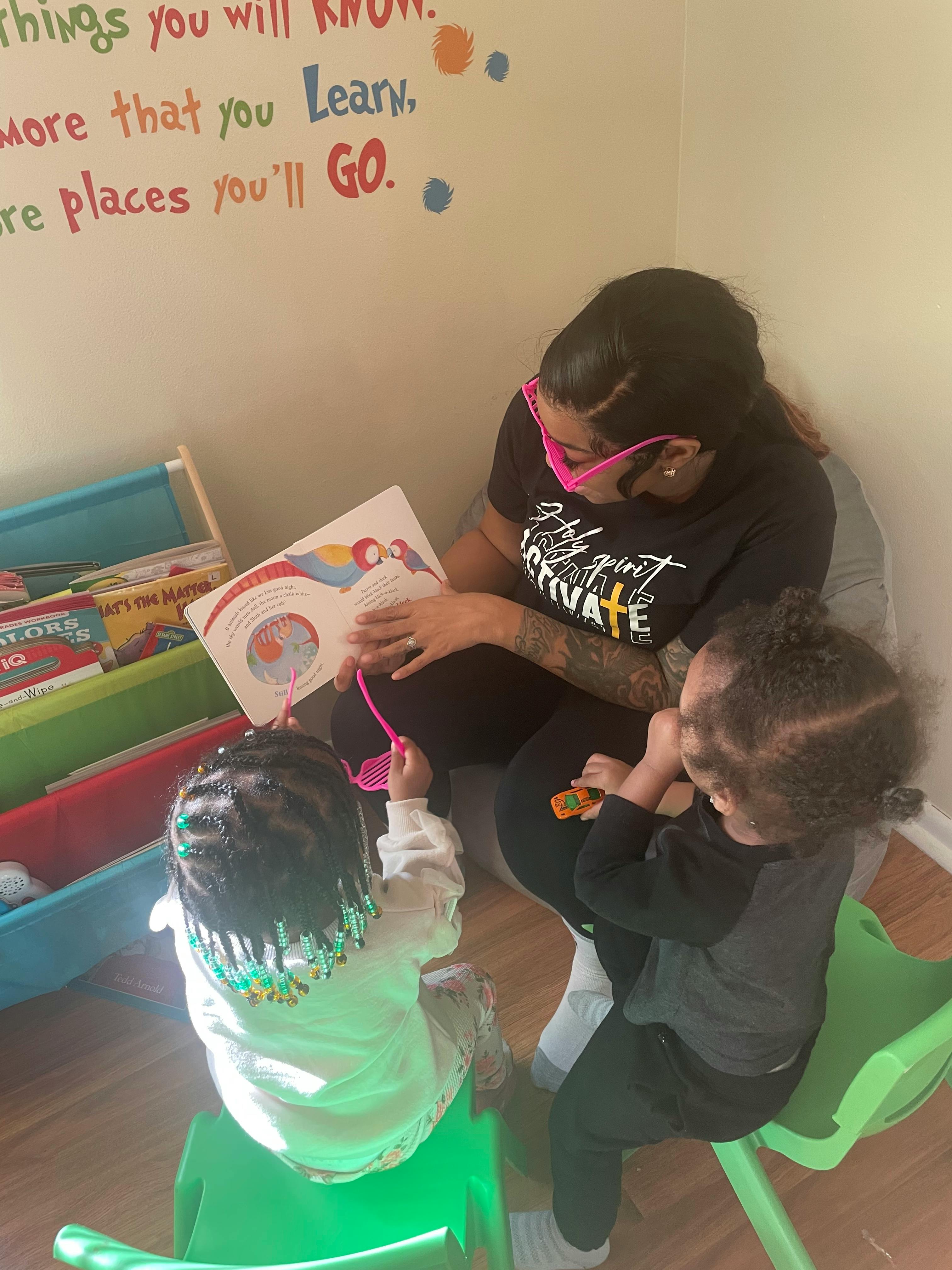 Person reading a book to two children