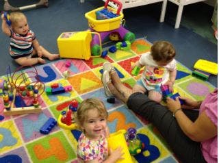 Three children playing with toys on a colorful rug