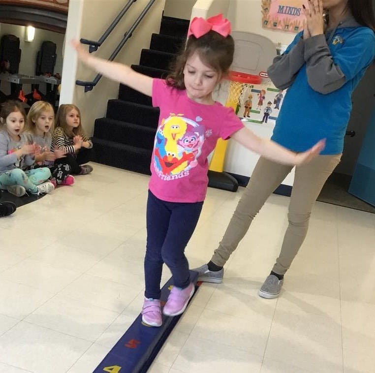 Child balancing on a beam with arms outstretched
