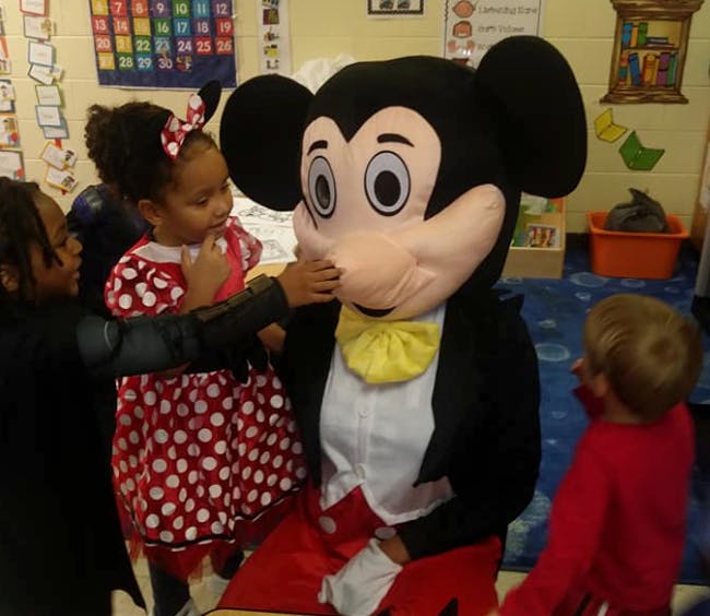 Children interacting with a person in a Mickey Mouse costume