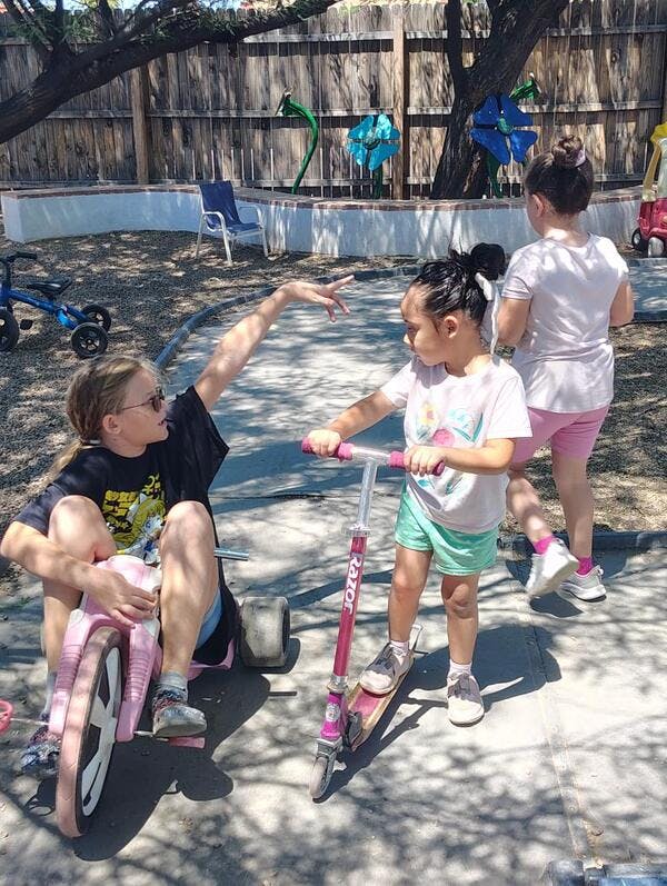 Children playing with a tricycle and scooter outdoors