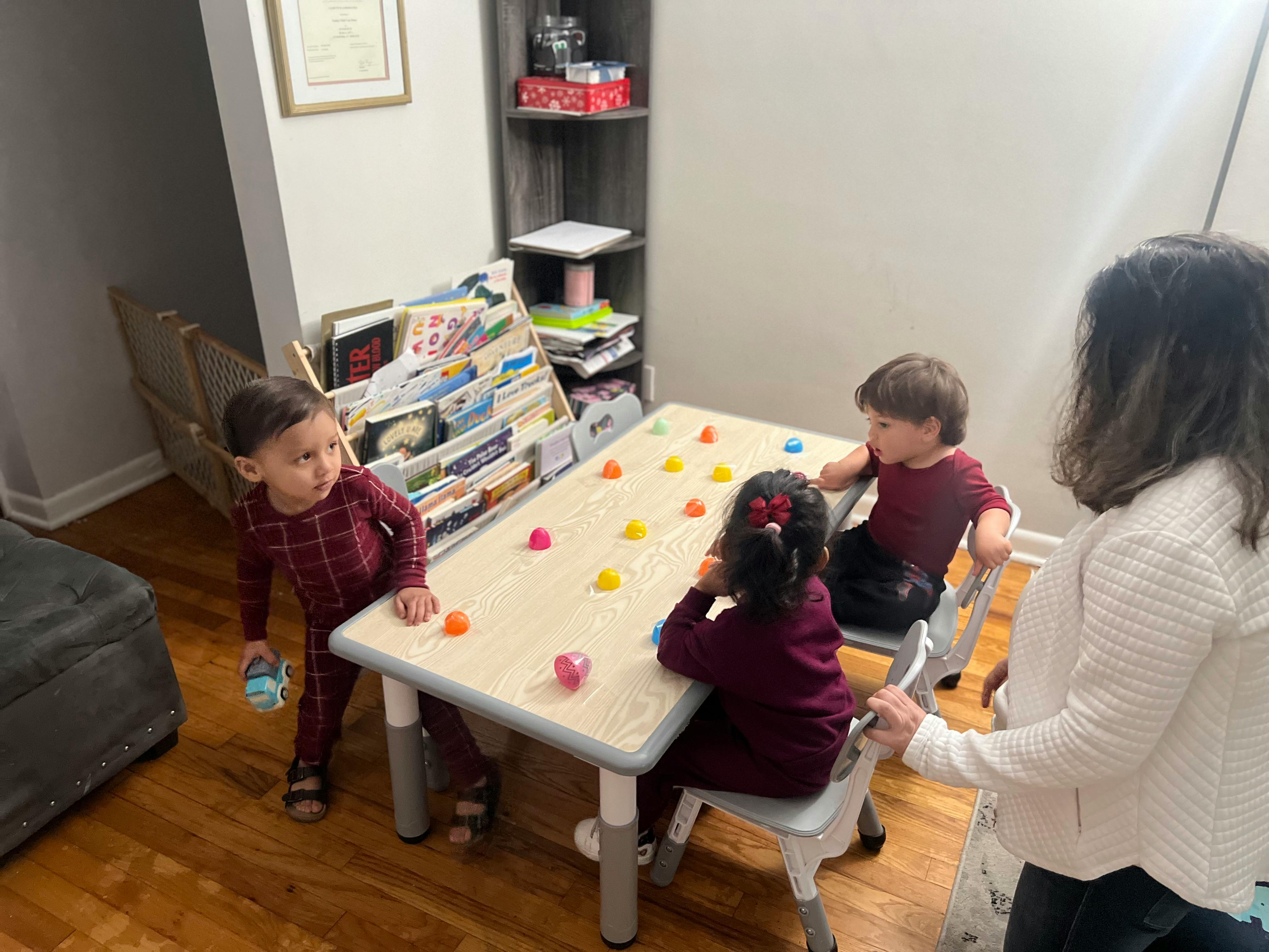 Adult and three children around a table with colorful objects