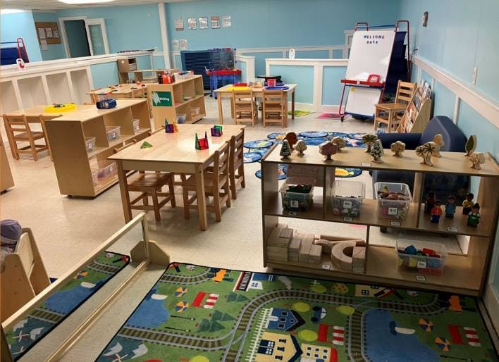 An empty classroom with light blue walls and wooden tables and shelves
