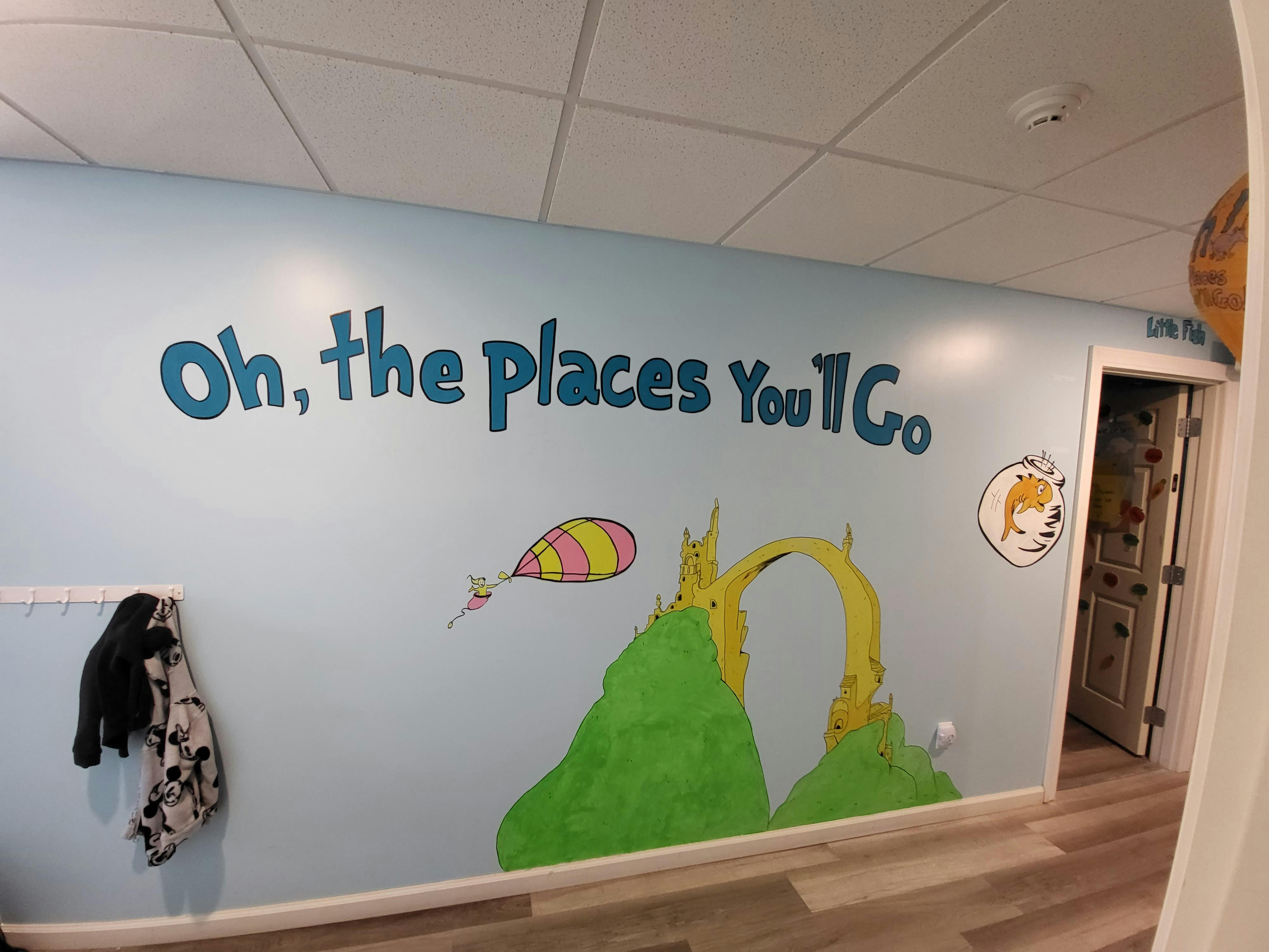 Wall mural with "Oh, the places You'll Go" text and Dr. Seuss-style illustrations