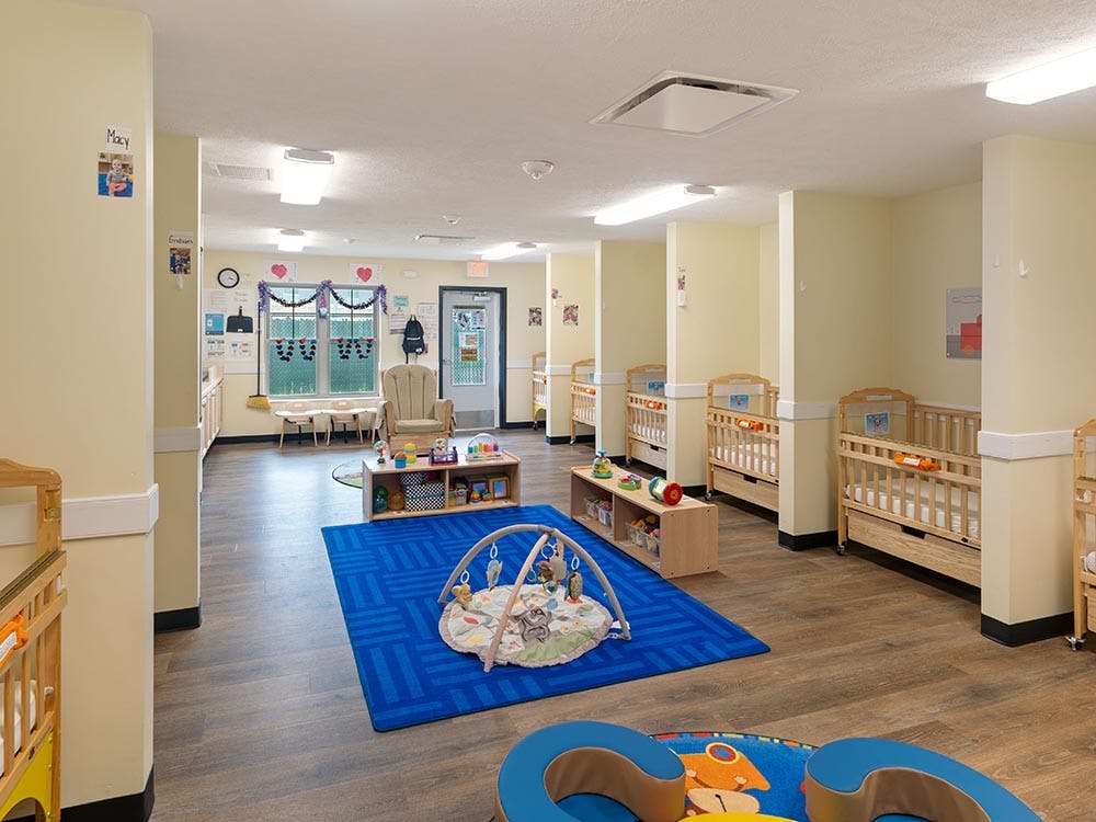 Cribs and play area in a brightly lit infant classroom