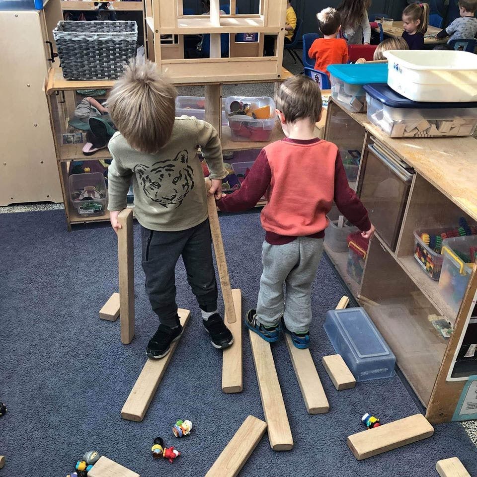Two children playing with wooden planks on the floor