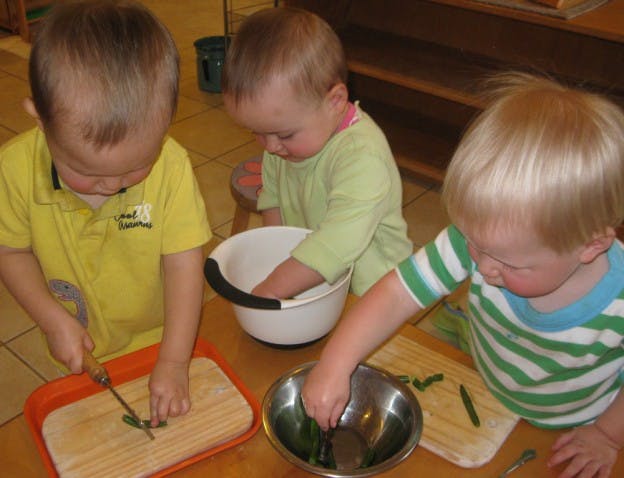Three children preparing food with bowls and cutting boards