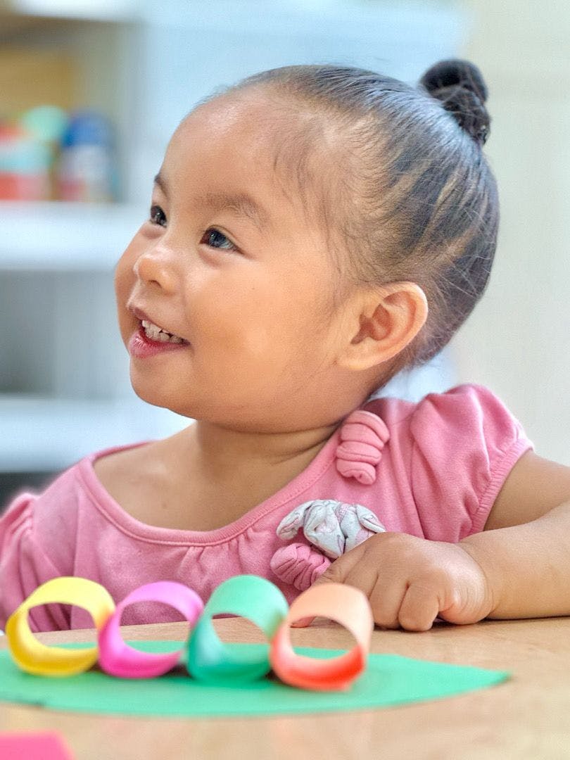 Child looking up with colorful rings on a table