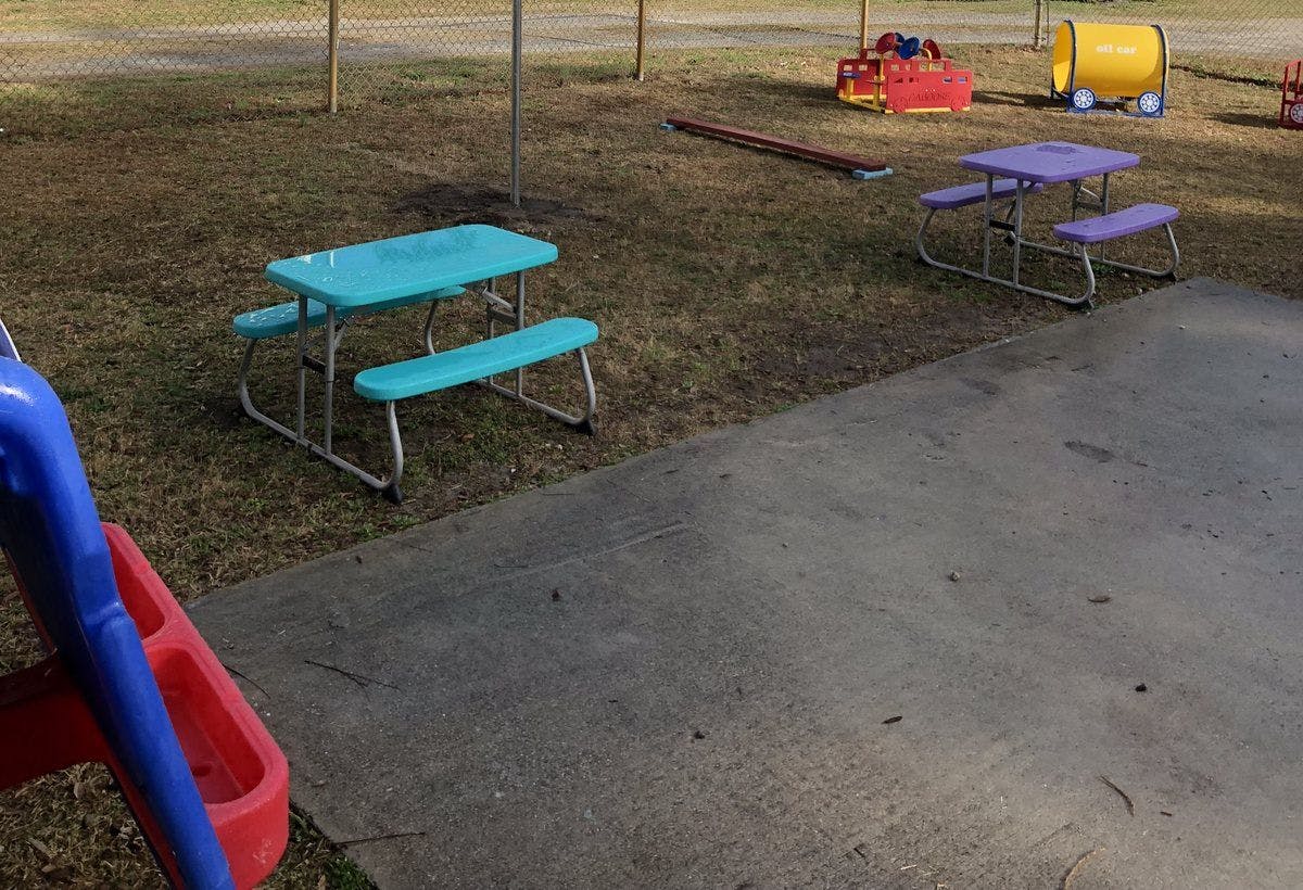 Two picnic tables and playground equipment on grass and concrete