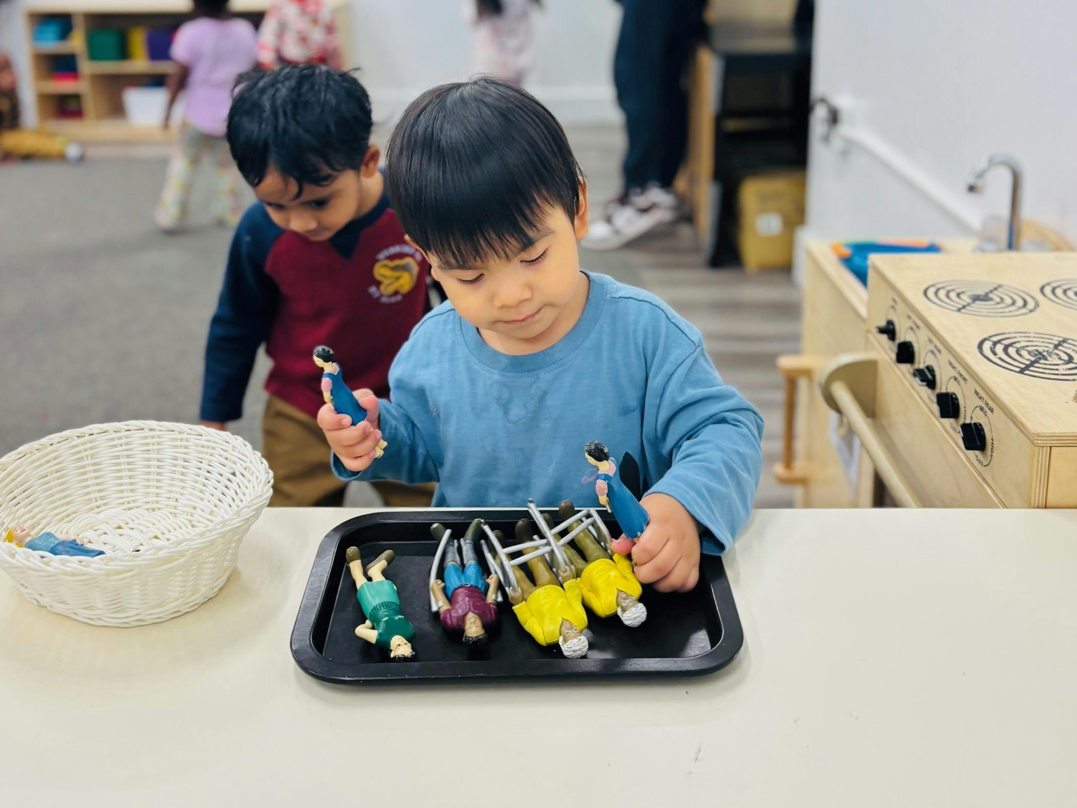 Child playing with dolls of people and walkers in a classroom
