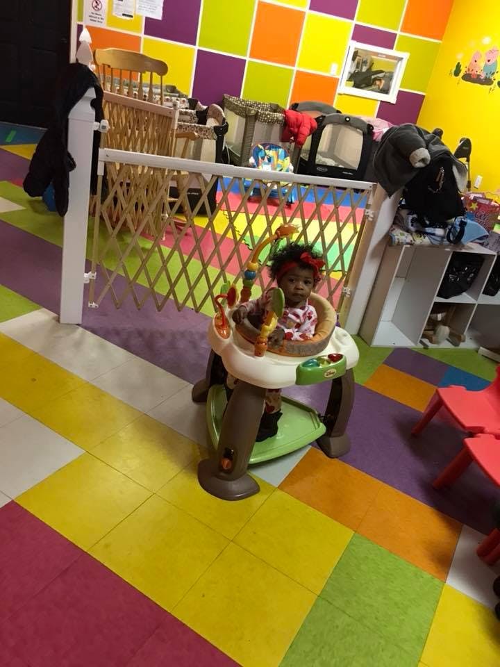 Child in a baby activity center in a room with colorful walls and patterned walls