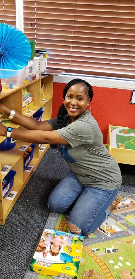 Person kneeling on a rug next to a bookshelf
