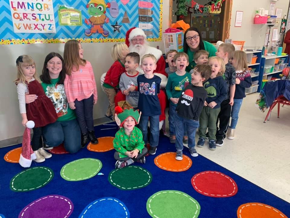 Santa Claus and adults with a group of children in a classroom