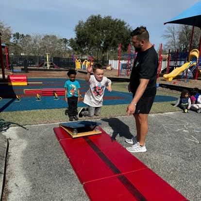 Adult and two children on a playground with a red mat