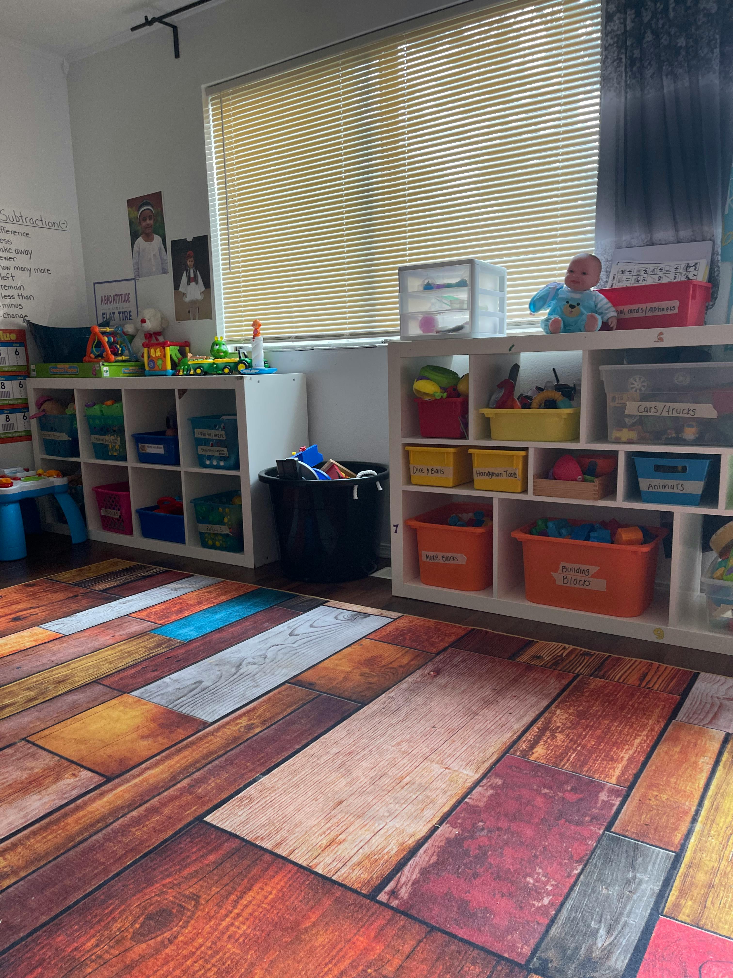Playroom with shelves of toys and a wood-patterned floor