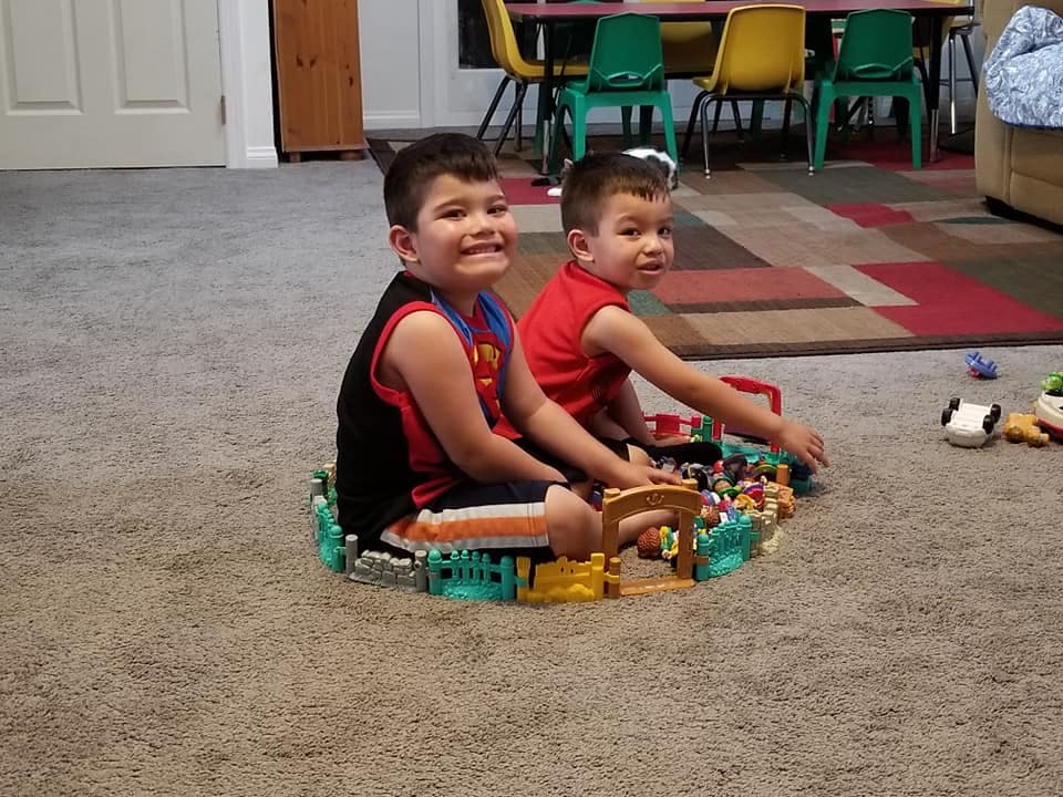 Two children playing with toys on a carpeted floor