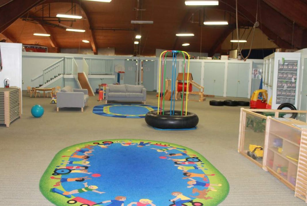Indoor play area with colorful rugs, seating, and play equipment