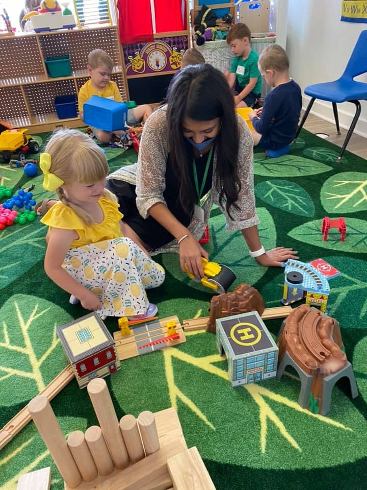 Adult and child playing with toys on a leaf-patterned rug