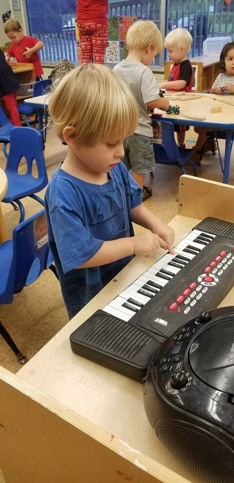 Child playing a toy keyboard in a classroom