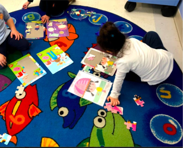 Child playing with puzzles on a fish-themed rug