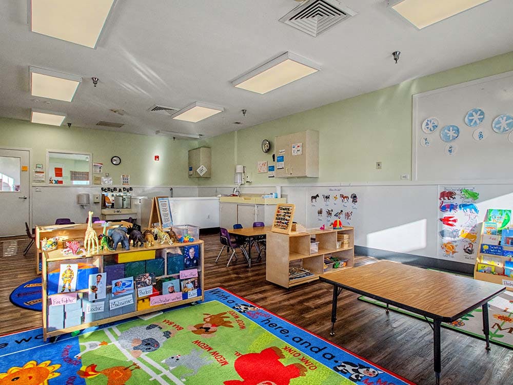 Classroom with child-sized furniture and colorful animal rug