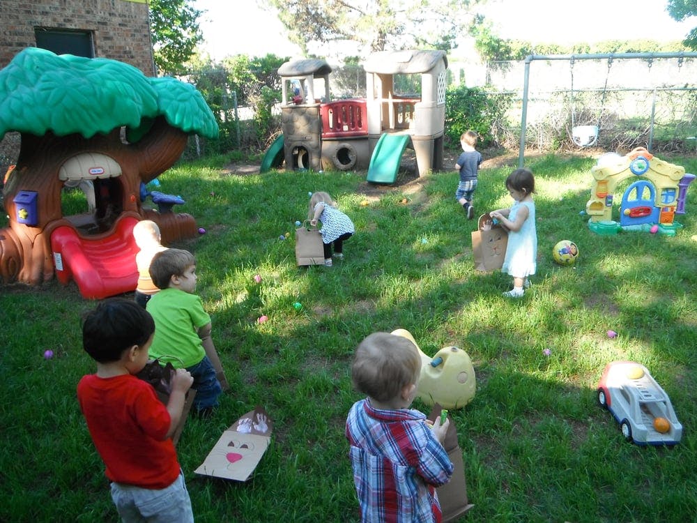 Children playing outdoors in a grassy area with play structures