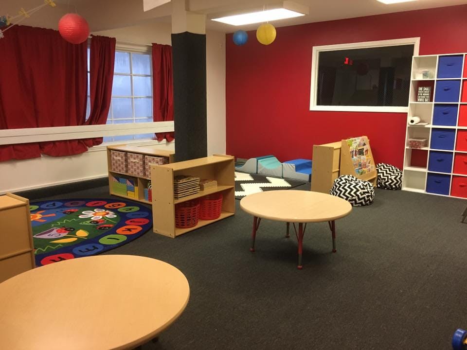 Classroom with small tables, shelves, and a colorful rug