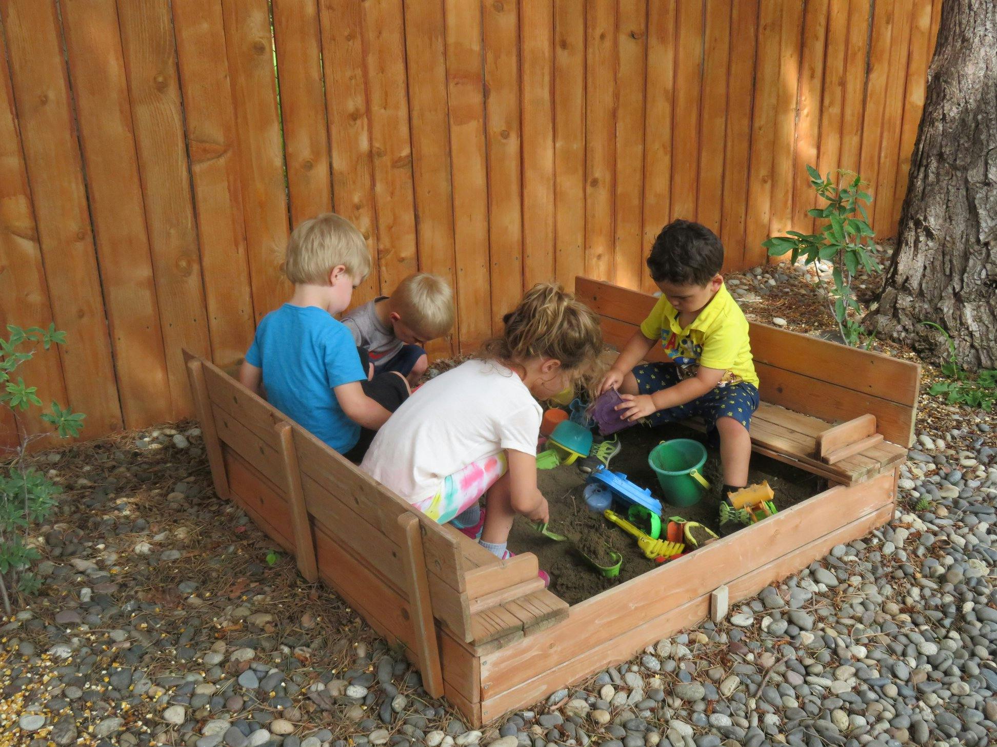 Children playing in a sandbox with toys