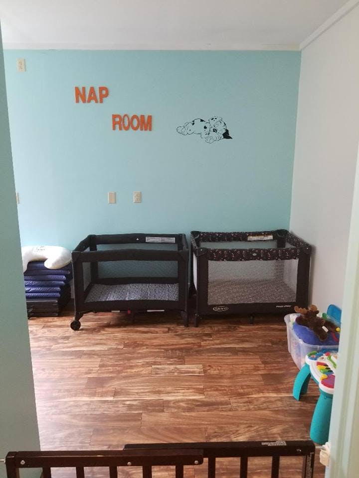 Two portable cribs in a room with "NAP ROOM" on the wall