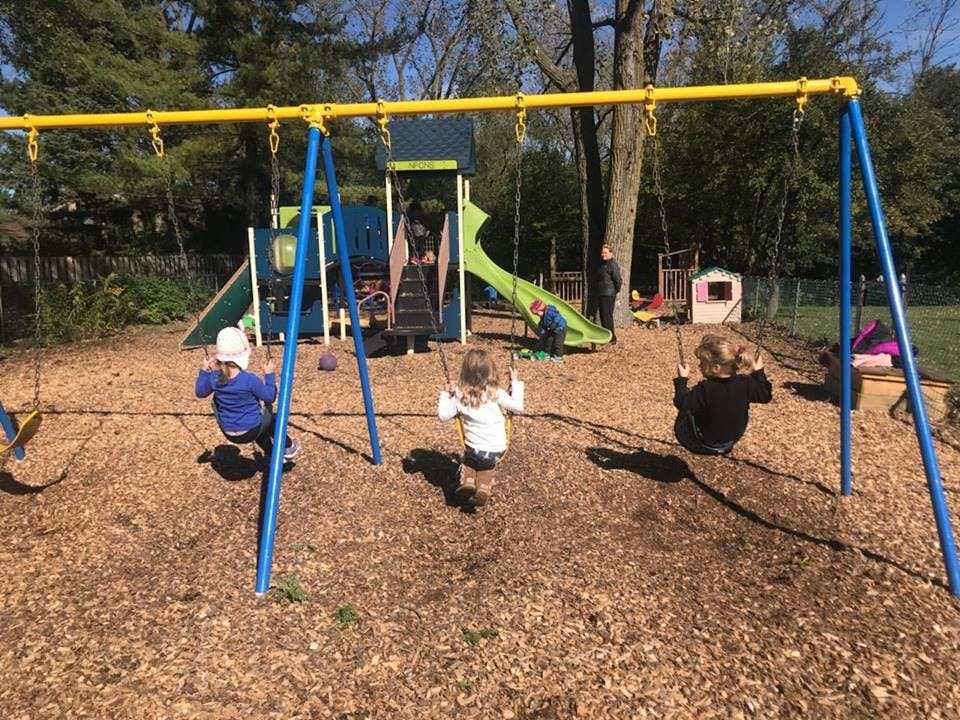 Children playing on swings and a playground structure