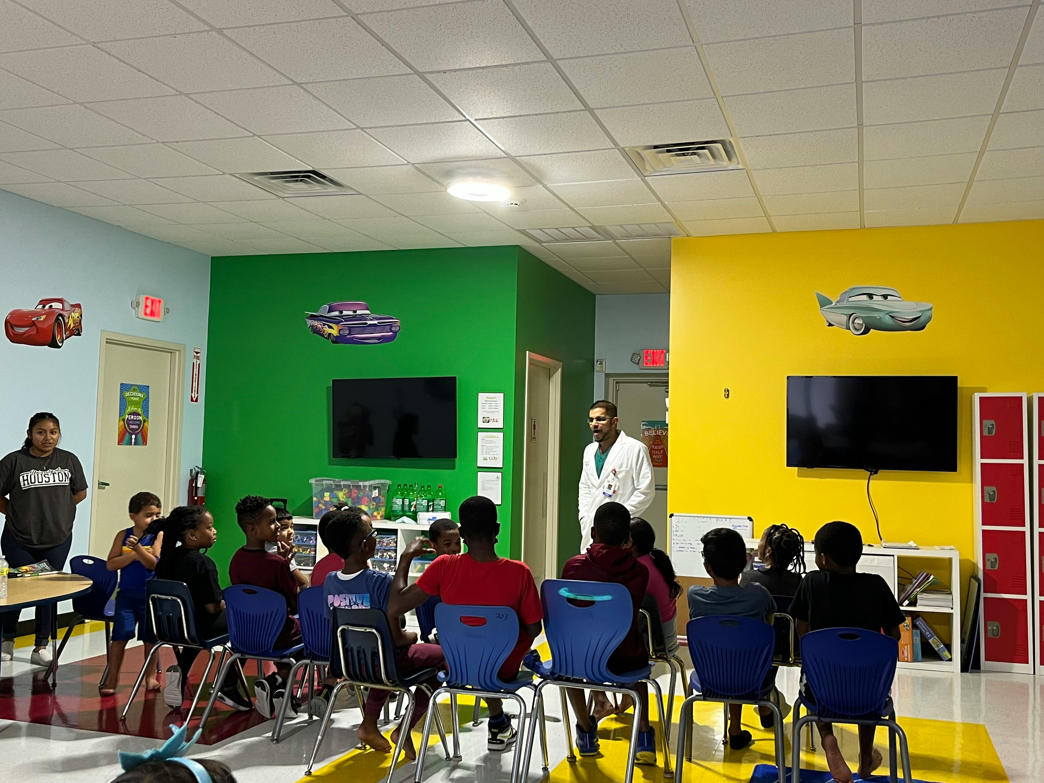 Adult speaking to a group of children seated in a classroom