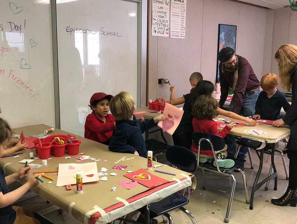 Adults and children doing crafts at tables in a classroom