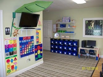 Classroom with TV, wall charts, storage bins, and small table with chairs