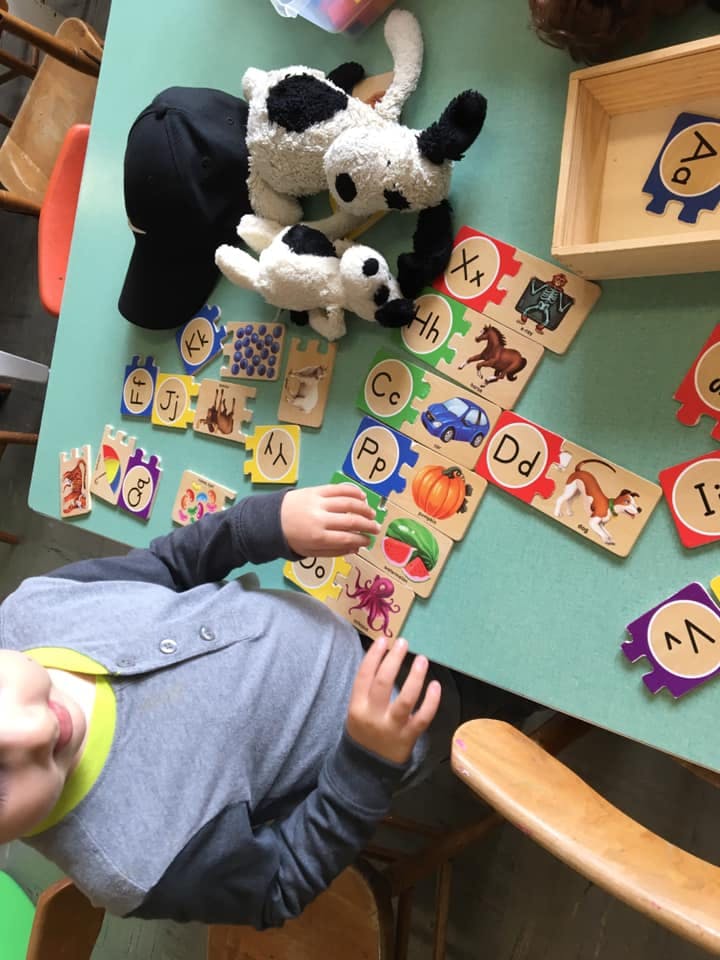 Child playing with alphabet puzzle pieces on a table